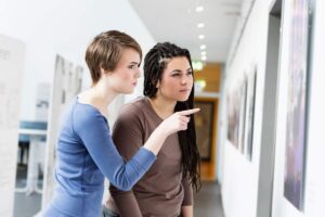 Due ragazze che osservano i quadri di una mostra